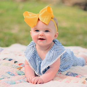 A baby laying down on a mat outdoors in tummy time